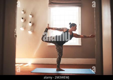 Life is all about being in balance. a young woman practising yoga at home. Stock Photo