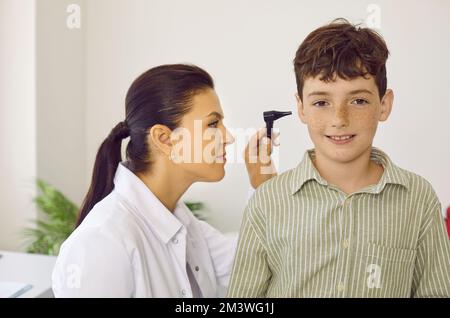 Otorhinolaryngologist uses otoscope to examine child's ear during medical examination in hospital. Stock Photo