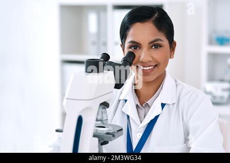Nothings too small to see. Cropped portrait of an attractive young female scientist smiling while working with a microscope in a laboratory. Stock Photo