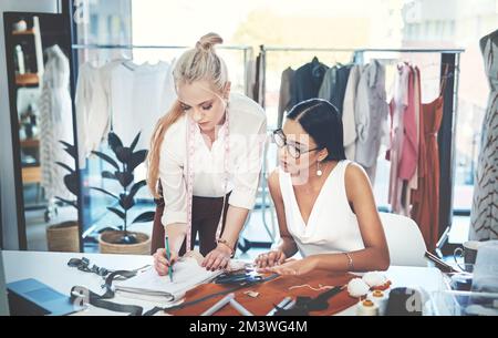 Were working together to create a masterpiece. two young fashion designers working together in a workshop. Stock Photo