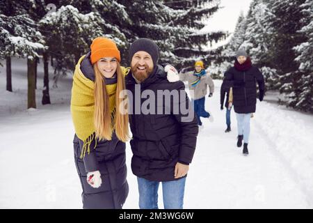 Portrait of smiling happy couple together with friends on winter walk in snowy forest. Stock Photo