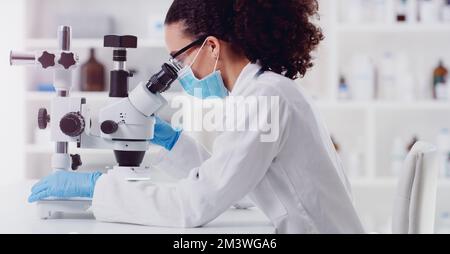 Testing some new samples. a young scientist using a microscope in a lab. Stock Photo