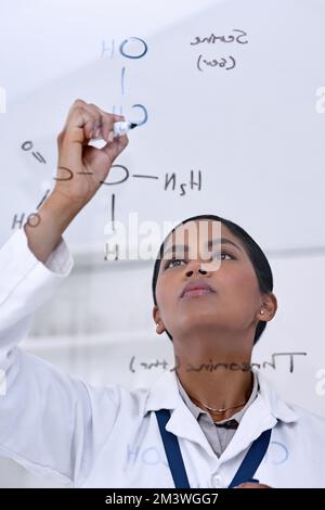Putting it all up on the board. an attractive young female scientist working on formulas in her laboratory. Stock Photo