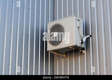 The external unit of the air conditioner is installed on the facade of the house. The wall is made of profiled metal Stock Photo
