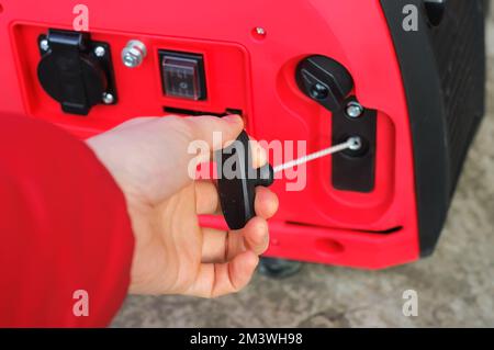 I start the gasoline inverter generator by hand, the red body has Honda written on it. Energy accident in Ukraine due to the war Stock Photo