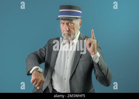 The conductor warns the passenger about the time of departure of the train. On a blue background. Stock Photo