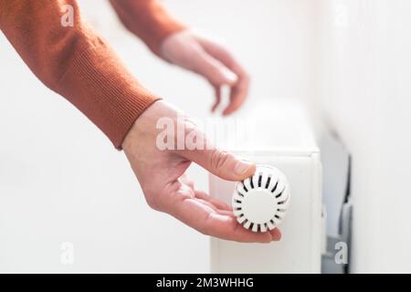 hand adjusting radiator temperature using thermostat. Home with central heating. Stock Photo