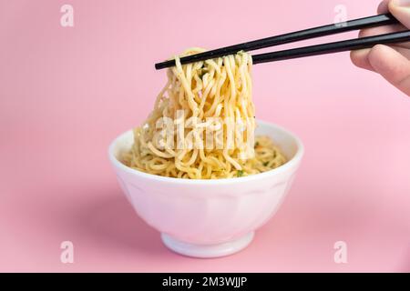 White bowl of noodles on an pink background, fast cheap food. Chinese instant noodles. Asian food. Stock Photo