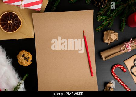 Blank Brown Paper Page on Black Wood Table with Christmas Decoration. Mock Up of Letter to Santa Claus. Top View of Jolly Father Desk with Envelopes, Stock Photo