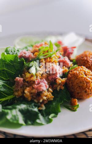A Lao dish consisting of deep-fried rice broken apart, topped with som moo/nam (fermented sour pork), and fresh herbs. Stock Photo