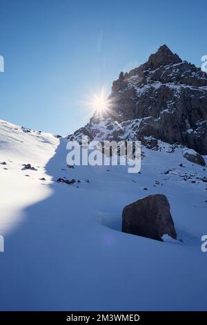 Sunny day at high snow mountains landscape with sun glow flare against blue sky at winter time in Kazakhstan Stock Photo