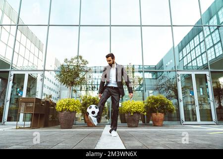 Image of a businessman and soccer freestyle player making tricks with the ball on the street. Concept about sport and business people Stock Photo
