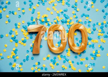 700 seven hundred followers subscriber card golden birthday candle on yellow and blue confetti Background. Template for social networks, blogs. celebration banner. 700 online community fans. Stock Photo