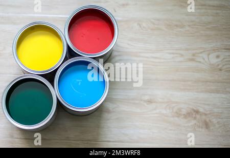 A top view of colorful four cans of paint ready for use on a wooden table Stock Photo
