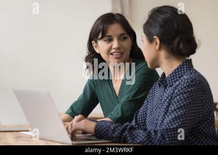 Cheerful multiethnic business colleagues women talking at laptop Stock Photo