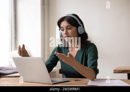 Engaged online teacher, coach giving workshop, webinar, using laptop Stock Photo