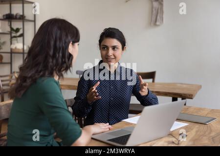 Positive pretty Indian mentor woman training intern, new employee Stock Photo
