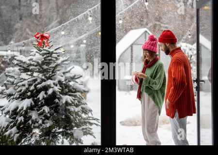 Young couple decorates Christmas tree at backyard Stock Photo