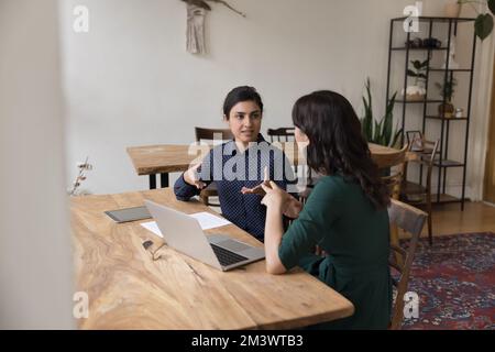 Serious Indian business leader woman talking to colleague at workplace Stock Photo