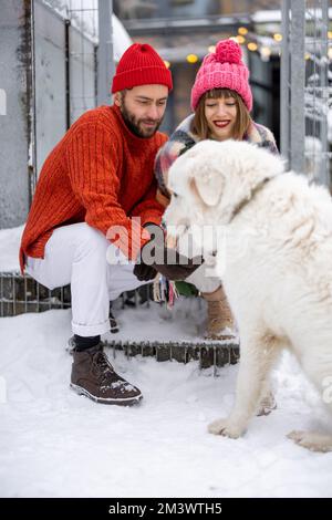 Young couple with dog on a porch of their house on winter Stock Photo