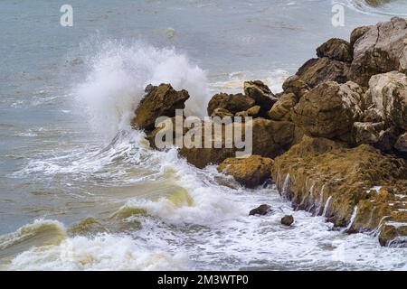 Strong waves crashing on the rocks off the coast of Gibraltar on a cloudy day and rough seas. Stock Photo