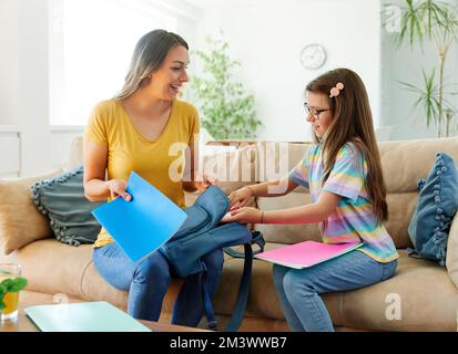 child mother family education school girl home daughter backpack help parent getting ready elementary teen morning hug love helping together Stock Photo