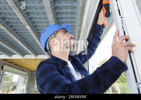workman using cordless drill on pvc door Stock Photo