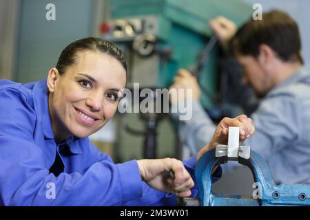 woman using a bench vice in a factory Stock Photo