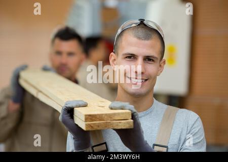 2 workers carrying wooden planks Stock Photo