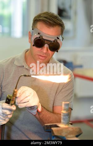 man wearing protective eyewear using gas torch Stock Photo