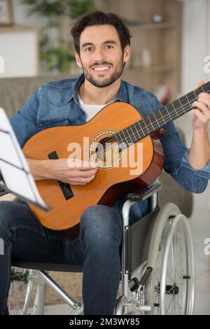 disabled man playing guitar at home Stock Photo