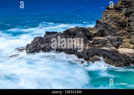 A beautiful scene of the blue ocean waves crashing on the cliffs in Halona Cove, Oahu, Hawaii Stock Photo