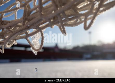 close up of melting ice on goal net on football pitch covered with snow. Stock Photo