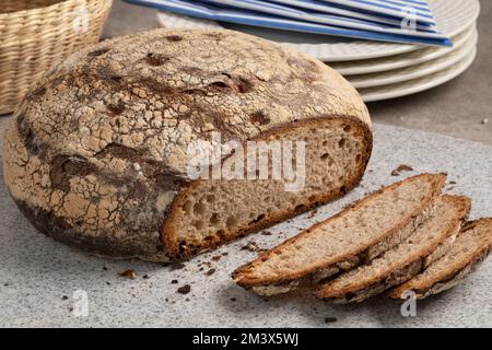 Fresh traditional German whole Bauernkloben brot, and slices, mixed rye loaf of bread, close up on a cutting board Stock Photo
