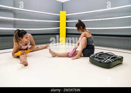 A young student practicing punching with her trainer in a kickboxing practice inside the ring Stock Photo