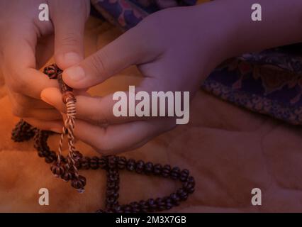 Prayer hands of a woman holding a rosary, with space for text, praying with a beat, Young Muslim girl with a rosary praying on Praying mate Stock Photo