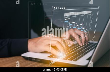Project manager working on laptop and updating tasks and milestones progress planning with Gantt chart scheduling interface for company on virtual scr Stock Photo