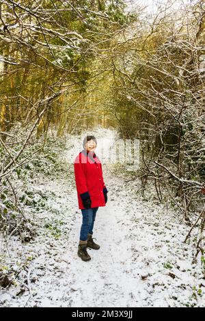 Active senior woman enjoying a winter walk through snow in the Princess Anne park, Washington, north east England, UK Stock Photo