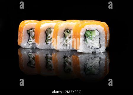 Uramaki Philadelphia classic isolated on black background. Salmon, Philadelphia cheese, cucumber avocado tobiko Stock Photo