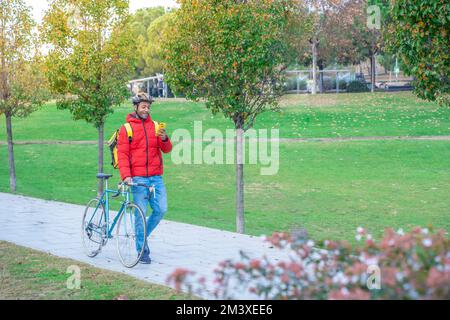 Food delivery concept. Smiling African American driver with backpack looking smartphone in the city Stock Photo
