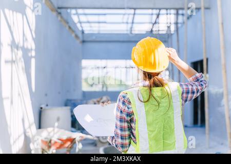 Female engineer working women. Architect construction builder worker with floor plan at building site. Stock Photo