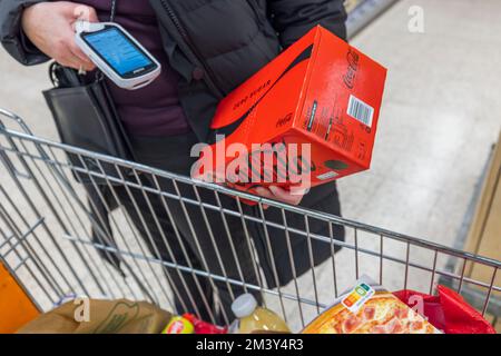 Close up view of woman buying pack of Coca Cola cans and scanning barcode. Sweden. Uppsala. Stock Photo