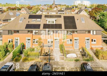 some houses with solar panels on the roof and cars parked in front of them, all facing towards each other buildings Stock Photo