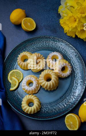 A vertical closeup of mini vanilla bundt cakes on a blue plate Stock Photo
