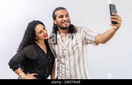 Young latin couple smiling happy and making selfie in isolated background Stock Photo