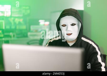 Hacker working on laptop preparing a cyber attack in dark room Stock Photo