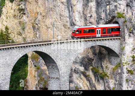 Bernina express glacier train on Landwasser Viaduct, Filisur, Switzerland. View of high railroad bridge and tunnel in rock of Swiss Alps. Theme of mou Stock Photo