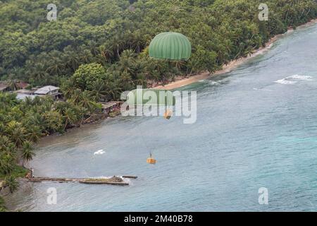 Murilo island, Federated States of Micronesia. 06 December, 2022. Humanitarian bundles parachute to a lagoon from a Japan Air Self-Defense Force C-130H Hercules aircraft assigned to the 401st Tactical Airlift Squadron, during Operation Christmas Drop, December 6, 2022 in Murilo island, Chuuk, Micronesia. Operation Christmas Drop is the oldest humanitarian and disaster relief mission delivering 71,000 pounds of food, gifts, and supplies to assist remote island communities in the South Pacific.  Credit: Yasuo Osakabe/US Airforce Photo/Alamy Live News Stock Photo