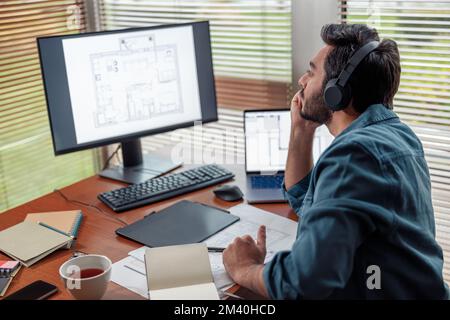 indian male designer in headphones works in home office drawing on graphic tablet Stock Photo