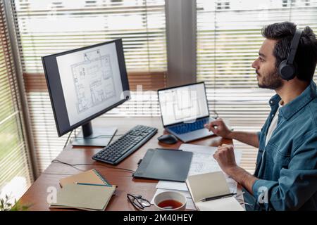 indian male designer in headphones works in home office drawing on graphic tablet Stock Photo